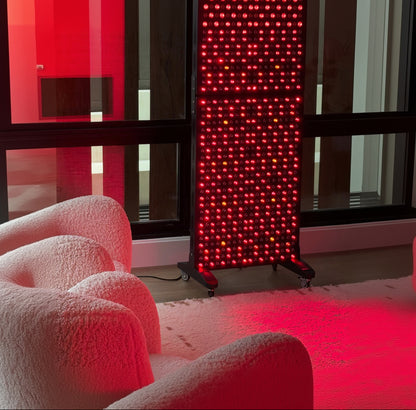 Red light therapy panel in a room with modern chairs and a window.