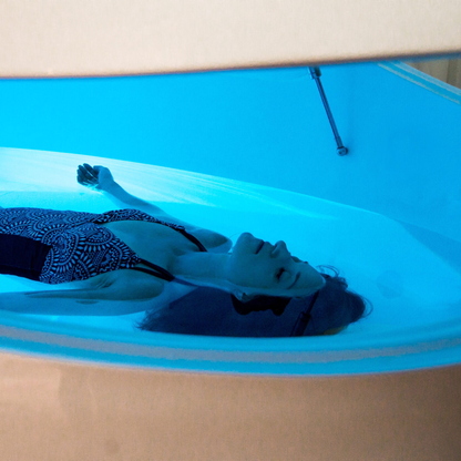Person lying in a flotation tank with blue light