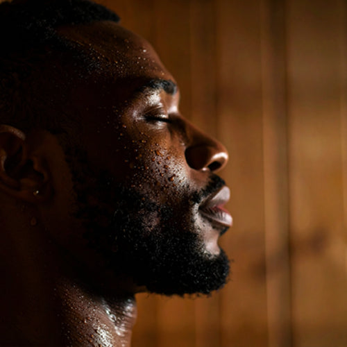 a man sitting and relaxing in the Baldwin 2-Person Traditional Sauna with his eyes clsoed